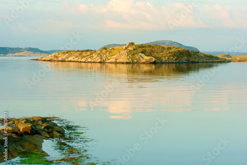 Small rocky islet in windless sea one evening in early fall. The Swedish west coast.