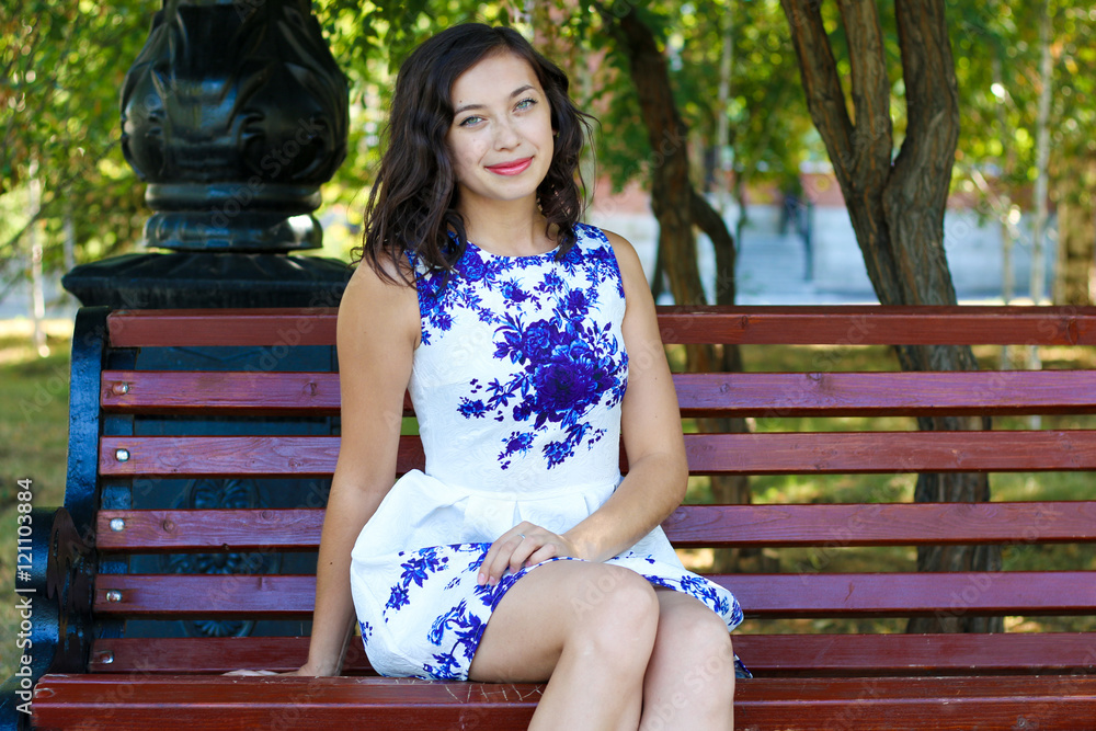 Beautiful young woman sitting on a park bench Stock Photo | Adobe Stock