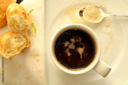 vista dall'alto di una tazzina di caffè espresso italiano, con un cucchiaino di  zucchero di canna e cornetti ripieni di crema photo