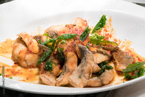 Fried fish in spicy curry sauce on white dish
 photo