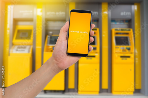 human hand hold smart phone, tablet, cellphone with virtual app internet banking on blurry cash Machine Background photo