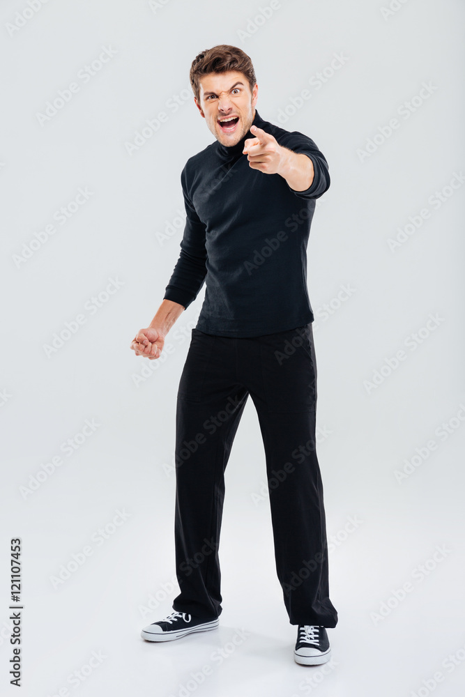 Mad irritated young man shouting and pointing on you Mad irritated young man shouting and pointing on you