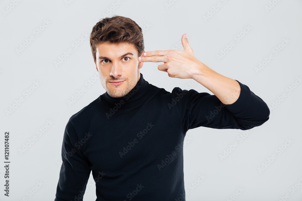 Serious man put fingers to his temple pretending a gun Serious man put fingers to his temple pretending a gun