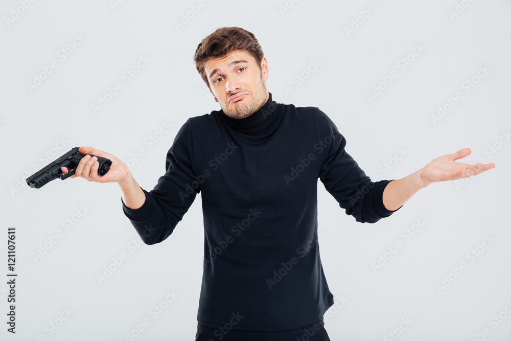 Confused young man with gun shrugging his shoulders Confused young man with gun shrugging his shoulders