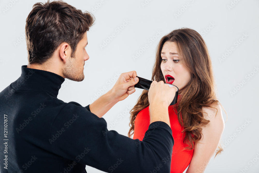 Criminal man covering mouth of scared woman with black tape Criminal man covering mouth of scared woman with black tape