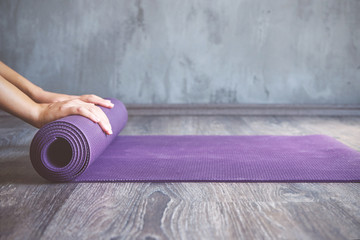 Fototapete Yogaschule Frau rollt ihre Matte nach einer Yogastunde  © SianStock