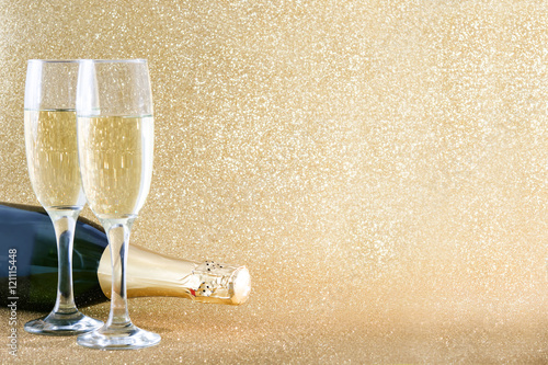 Champagne bottle with glass cups on brilliant golden background

