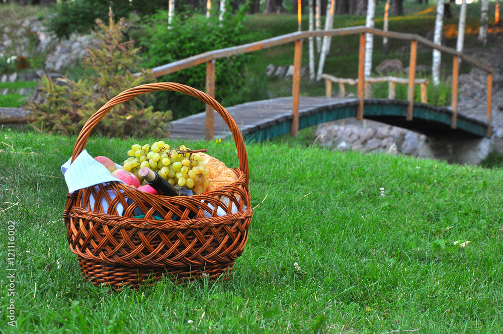 Closeup of picnic basket with drinks and food on the grass Closeup of picnic basket with drinks and food on the grass