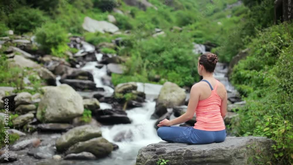 Woman meditating at tropical waterfall in Lotus pose Padmasana Woman meditating at tropical waterfall in Lotus pose Padmasana