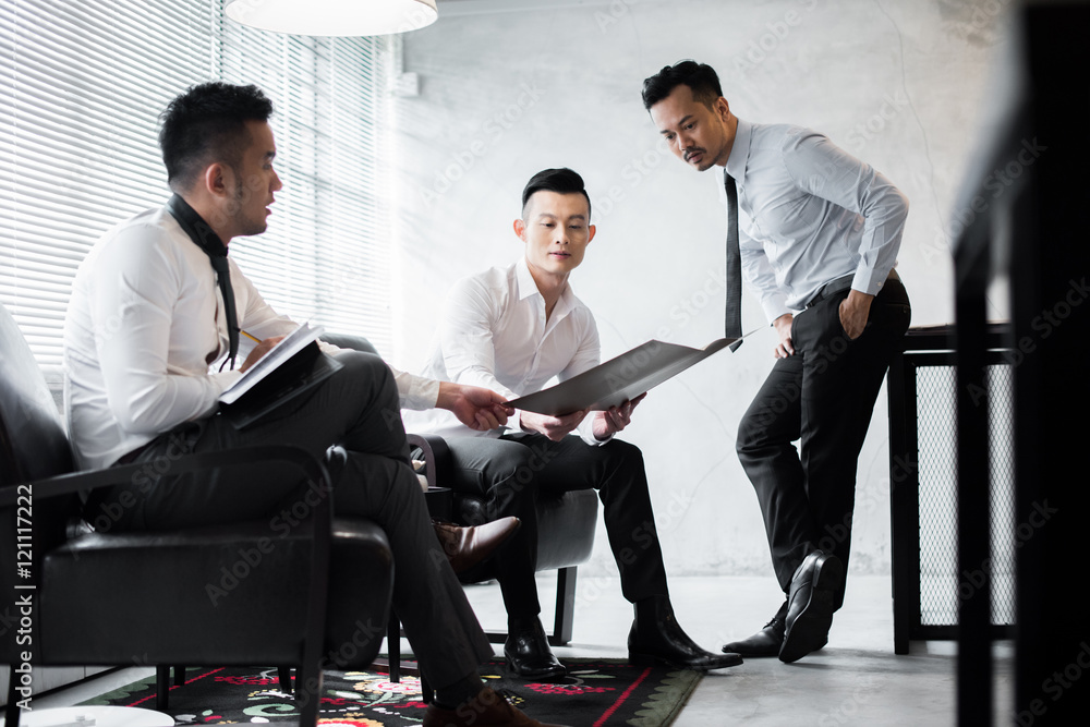 Three young coworkers discussing work in the office Three young coworkers discussing work in the office