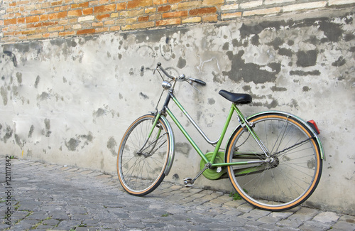 Green Old retro bicycle leaning against a wall