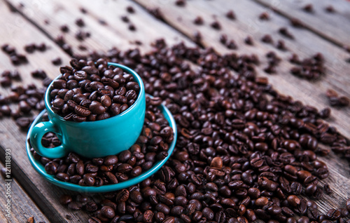Turquoise cup with coffee beans on a wooden background. Beverage, tableware
