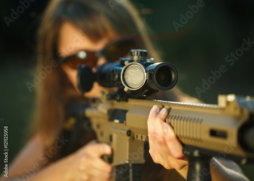 Obraz na plátne Girl with a gun for trap shooting and shooting glasses aiming at