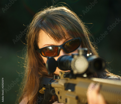 Foto Girl with a gun for trap shooting and shooting glasses aiming at