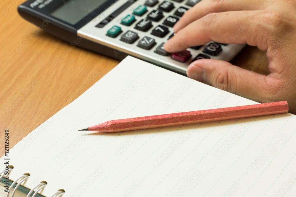 Business man place hand on calculator with pencil, book on wood Business man place hand on calculator with pencil, book on wood