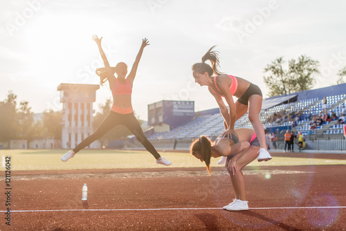 Fit women at the stadium playing leap frog.