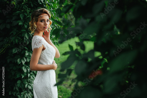 Elegant lady stands in a white lace dress between the walls of g