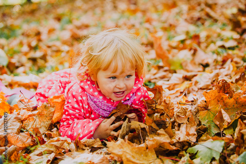 cute little girl playing with autumn leaves