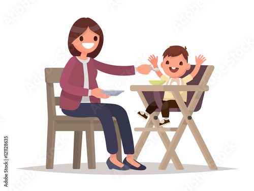Child Feeding. Mother feeds the baby sitting in the highchair. V