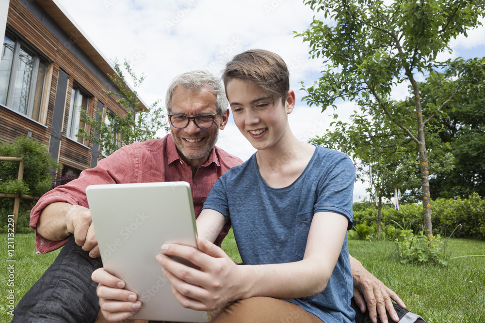 Happy father and son sharing digital tablet in garden Happy father and son sharing digital tablet in garden