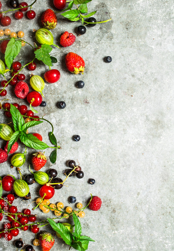 Berries with mint leaves on stone background.