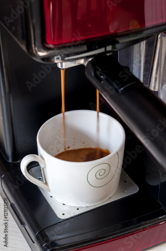 Cup with a little coffee. Espresso machine, coffee maker. Preparing coffee cup. Espresso machine pouring coffee in cup. Black coffee. Coffee falling from espresso machine. 