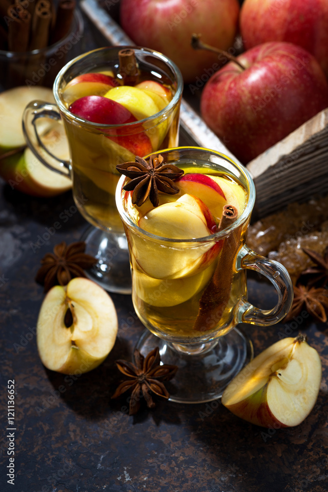 glasses of hot apple tea with spices on dark table, vertical glasses of hot apple tea with spices on dark table, vertical