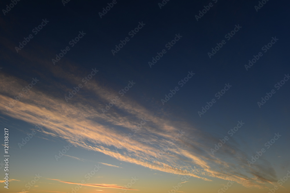 Blue sky with white stripe clouds in the sunset light