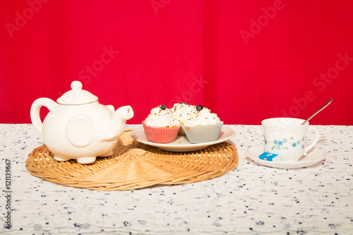 Cup of tea and sugar with teapot over red background