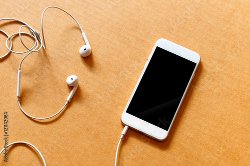 Blank white smartphone, and earphones on wooden background