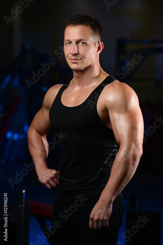 Handsome athletic fitness man posing and trains in the gym. © antondotsenko