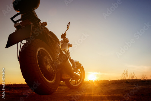 Motorbike stands on sunset backdrop sky road