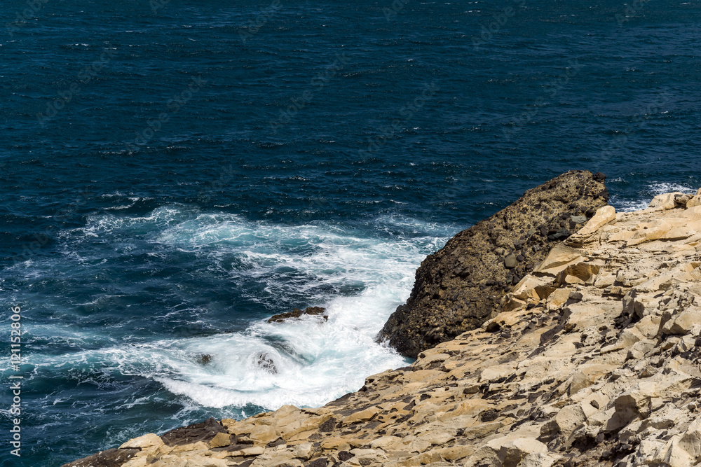 Daylight scene taken in a fischer vilage called Ajuy, located on the western coast of Fuerteventura, Spain. Very intensive blue color of the ocean with white foam hitting some rocks on the coast.