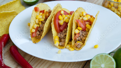 Homemade spicy mexican tacos cooked with chicken mince, tomato, chili and corn