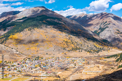 Aerial view of Silverton, Colorado in the fall with coal train and smoke with mountains and yellow aspen trees in the fall and clouds casting shadows