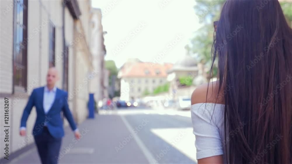 Young girl is checking up boy she passes by on the street.
