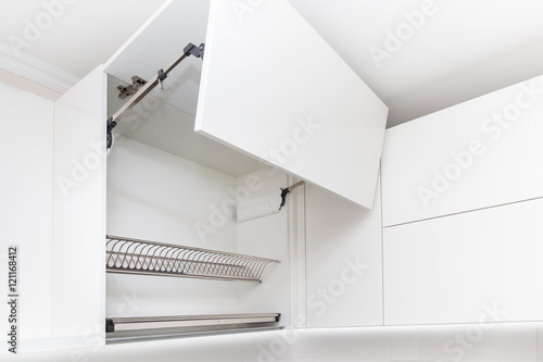 Kitchen cabinet with opened fronts with dish holder shelves inside. Lift system for bi-fold fronts for direct access in kitchen cabinets. 