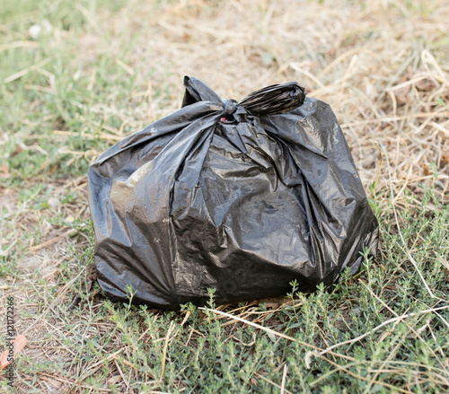black bag of trash on the ground © schankz