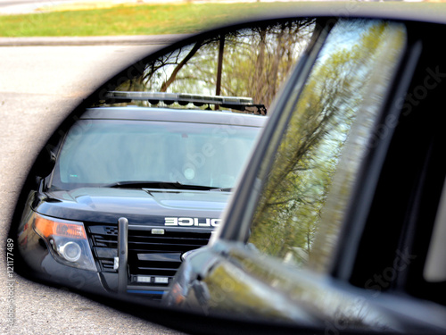 A police car has a motorist stopped for a violation. the drivers view from his side mirror