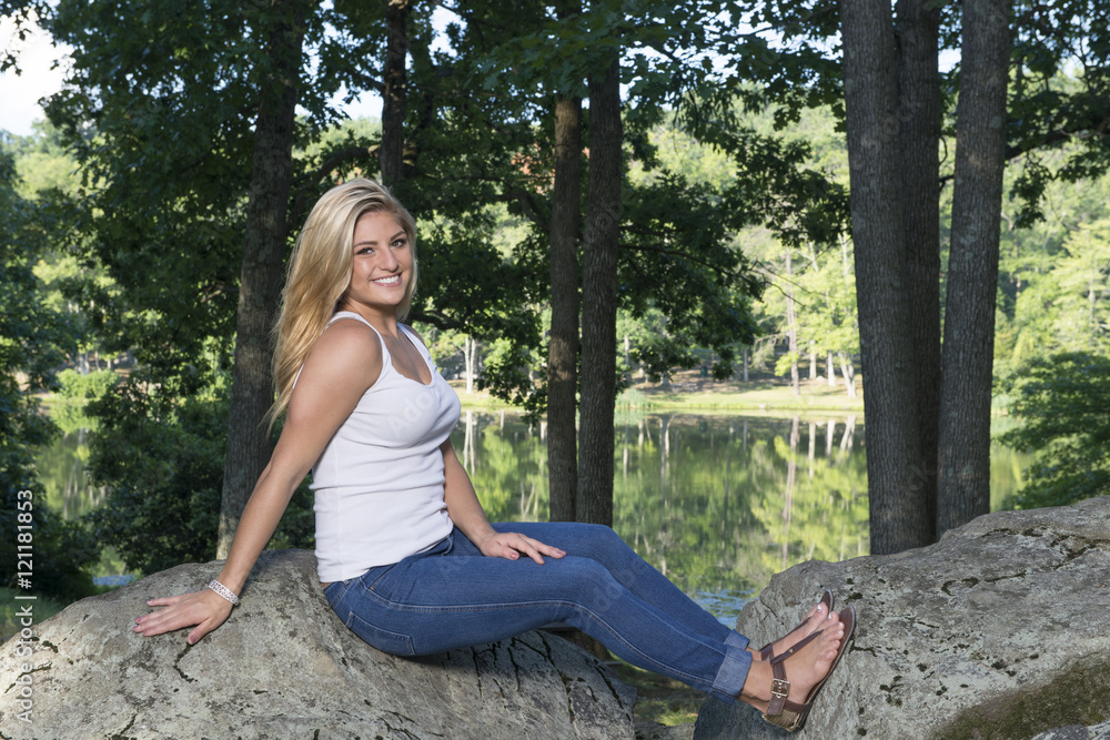 Beautiful young Caucasian woman in white tank top and denim (Blue jeans) poses in a park - model Beautiful young Caucasian woman in white tank top and denim (Blue jeans) poses in a park - model