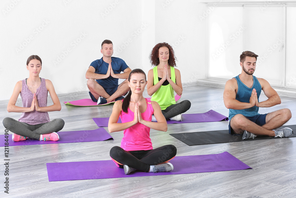 Group of people practicing yoga and meditating on mats Group of people practicing yoga and meditating on mats