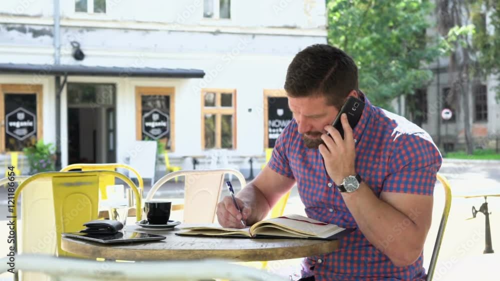 Man talking by smartphone makes notes to notebook. He is sitting at the table in cafe. He is young and has beard. Man is dressed in checkered shirt. Slider shot, right.
Man talking by smartphone makes notes to notebook. He is sitting at the table in cafe. He is young and has beard. Man is dressed in checkered shirt. Slider shot, right.