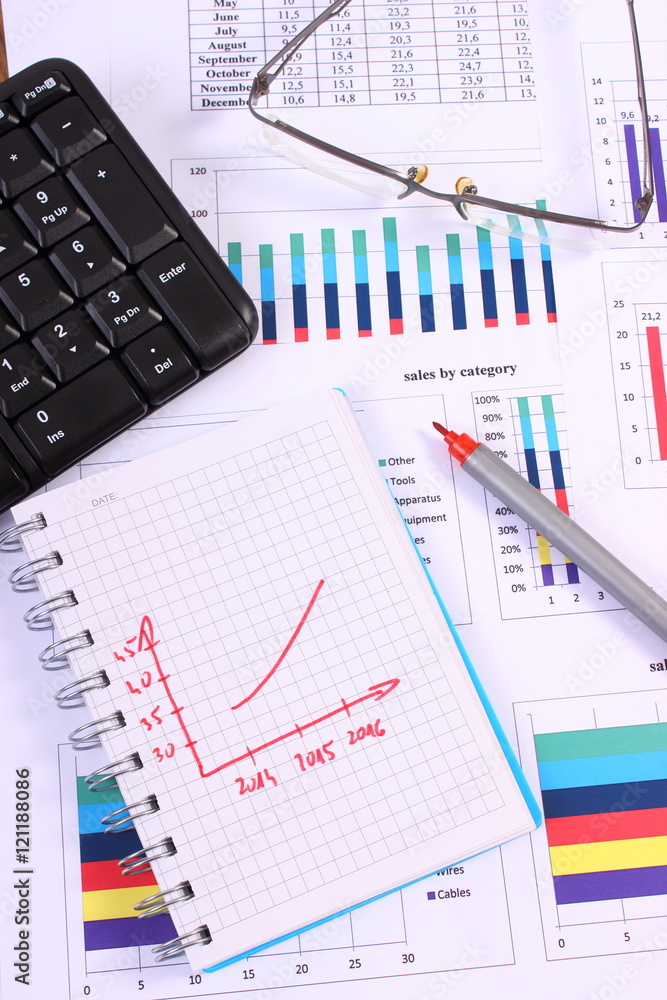 Pen, glasses and computer keyboard on financial graph, business concept Pen, glasses and computer keyboard on financial graph, business concept