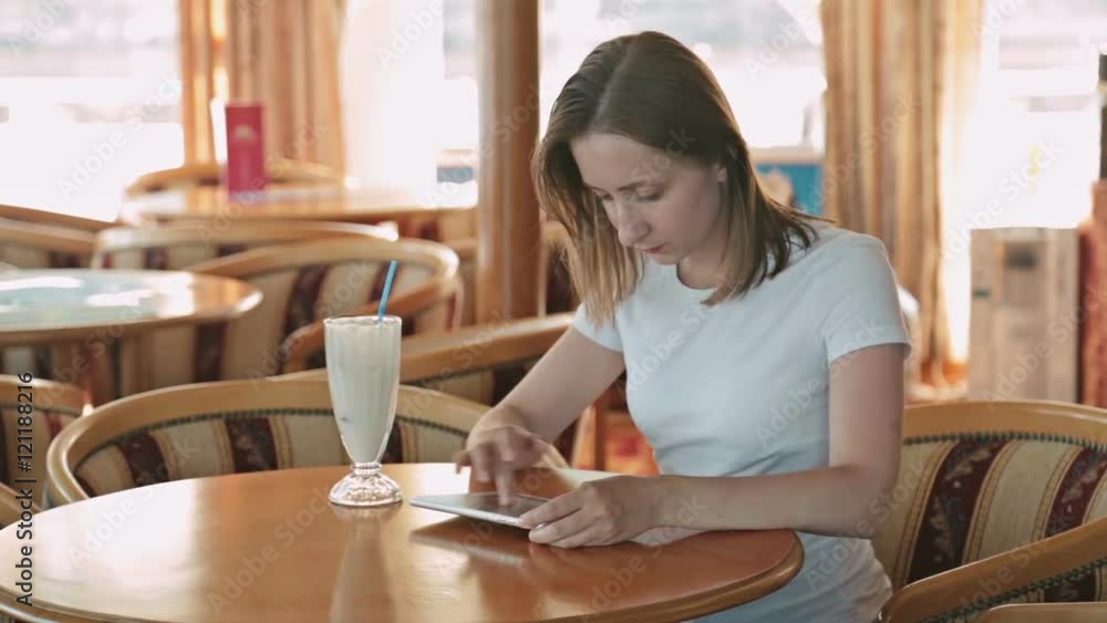 Woman using tablet computer touchscreen in cafe on cruise ship. Woman using tablet computer touchscreen in cafe on cruise ship.