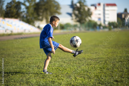 Boy kicking soccer ball on the football field