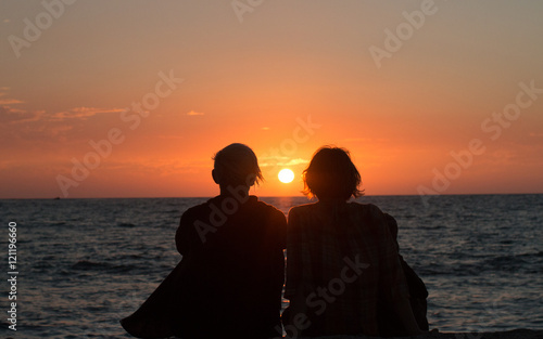 Two sisters watching the final sunset from a hawaiian vacation photo