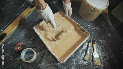 Worker picking a paint roller on a special tray.