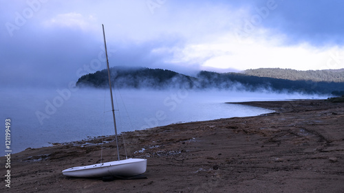 Alba sul lago Arvo con la nebbia ed una barca a vela photo