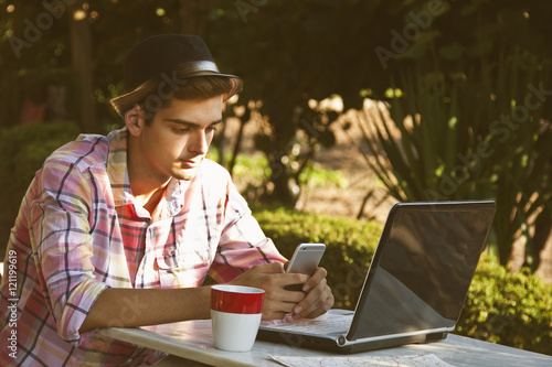 man with mobile phone and computer outdoors at sunset photo