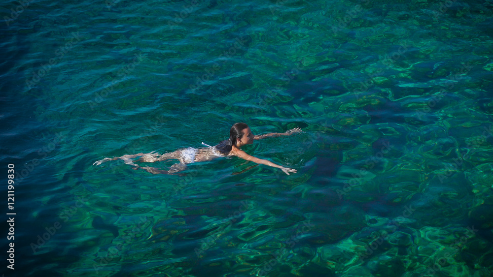 Young woman swimming in beautiful azure sea